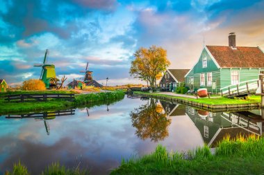 Hollanda 'nın geleneksel yel değirmeni Zaanse Schans yaz günbatımında su üzerinde, Hollanda