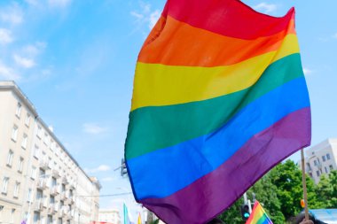 Gay pride parade, rainbow lgbt flags over people over city background