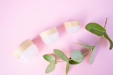 Doğal kozmetik konsepti, yumuşak pembe arka planda krema kavanozları