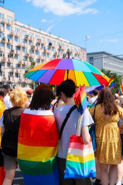 Gay pride parade, view of rainbow lgbt flags over people over city background