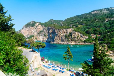 Paleokastritsa plaj koyunda güneşli yataklar ve Yunanistan 'ın Korfu kentinde İyon denizi açık suları