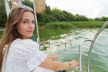 Neşeli bir kadın huzurlu suyun kenarında canlı çiçekler tutarak ve güzel manzaranın tadını çıkararak kutlama yapıyor.