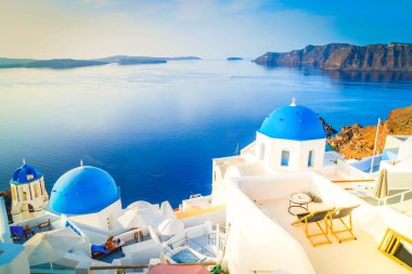Beyaz kilise çan kubbesi, parlak mavi kubbeler ve deniz manzaralı volkan kalderası, Yunanistan 'ın Santorini adasının güzel detayları
