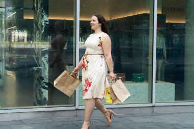 Ekolojik el sanatları alışveriş torbalarıyla dükkan vitrinine bakıp alışverişin tadını çıkaran mutlu kavisli kadın. Tüketim, alışveriş, yaşam tarzı konsepti