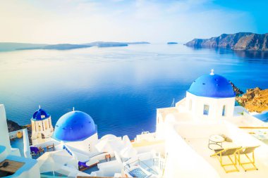 Beyaz kilise çan kubbesi, parlak mavi kubbeler ve deniz manzaralı volkan kalderası, Yunanistan 'ın Santorini adasının güzel detayları