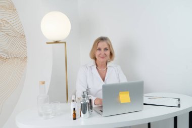 Son derece yetenekli profesyonel bir kadın modern ve şık bir çalışma alanı içinde bir dizi cilt ürününü zarif bir şekilde sunar.