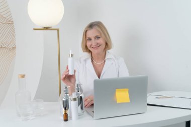 Son derece yetenekli profesyonel bir kadın modern ve şık bir çalışma alanı içinde bir dizi cilt ürününü zarif bir şekilde sunar.