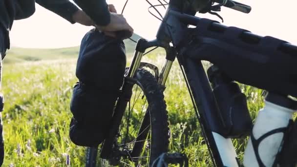 カザフスタンの緑の芝生の丘でマウンテンバイクで彼の観光バッグを閉じると男 エクストリームスポーツ自転車の自転車パッキングとアウトドア旅行のコンセプト — ストック動画