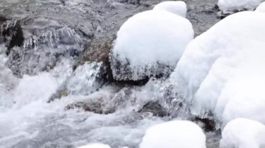 Mavi su nehri taşların arasından akar kış vakti dağlarda kar ve buzla birlikte yavaşça yaklaşır.