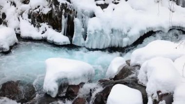 Mavi su nehri taşların arasından akar kış vakti dağlarda kar ve buzla birlikte yavaşça yaklaşır.