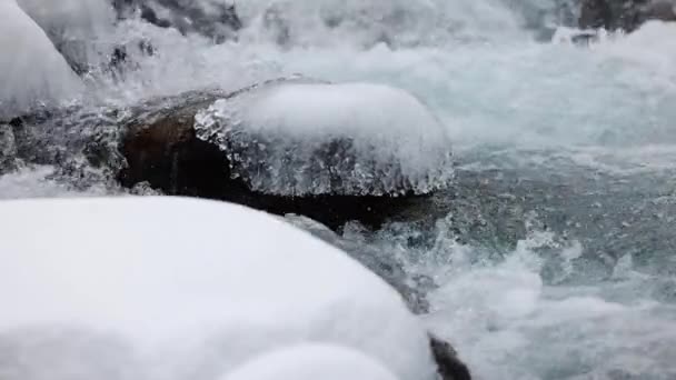 蓝色的水流在石头之间 冬天的时候 雪和冰在山上缓缓地逼近 — 图库视频影像
