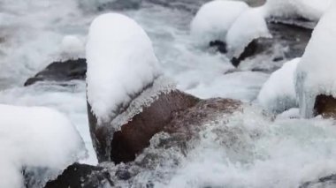 Mavi su nehri taşların arasından akar kış vakti dağlarda kar ve buzla birlikte yavaşça yaklaşır.