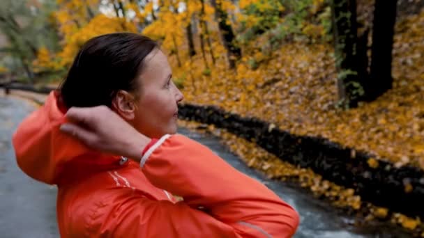 城市公园里穿着橙色外套 头罩跑步的女跑步者 黄色的树叶 枫树和湖水 健康的生活方式 — 图库视频影像