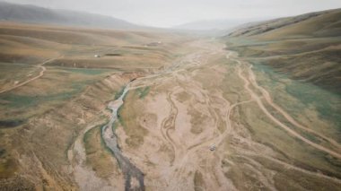 Kazakistan 'daki Assy Platosu' nda Orta Asya nehri yakınlarındaki dağlarda çakıllı yol boyunca giden off-road aracının üzerindeki hava aracı.