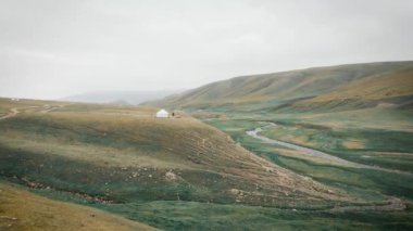 Orta Asya nehri yakınlarındaki dağlarda, Kazakistan 'daki Assy Platosu' nda beyaz yurt göçebe evinin üzerindeki hava aracı.