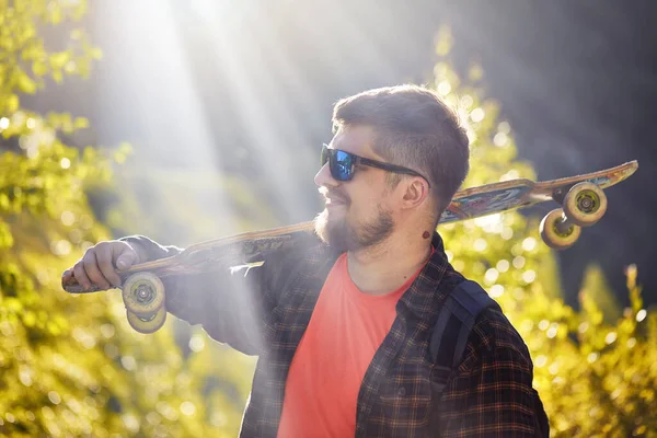 Portret Poważnego Brodatego Mężczyzny Łyżwiarza Okularach Przeciwsłonecznych Trzymającego Longboard Górskim — Zdjęcie stockowe