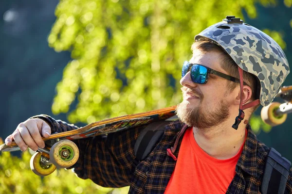 Portret Szczęśliwego Brodatego Mężczyzny Łyżwiarza Okularach Przeciwsłonecznych Kasku Trzymającego Longboard — Zdjęcie stockowe