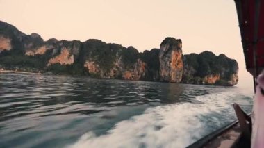 Andaman Denizi, Tayland 'da gün batımında Koh Phi Phi adalarına doğru hızla giden uzun kuyruklu bir tekne.