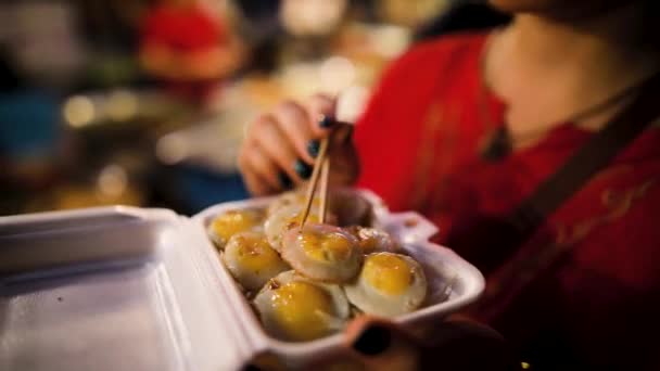 バンコクのナイトマーケットで中華箸でタイ料理を食べる白人の若い女性 — ストック動画
