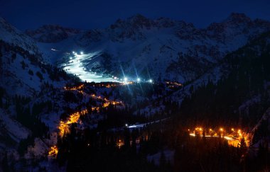 Landscape of glowing road from Medeu ice skate to Shymbulak ski resort at Tian Shan mountains at night time in Almaty city, Kazakhstan clipart