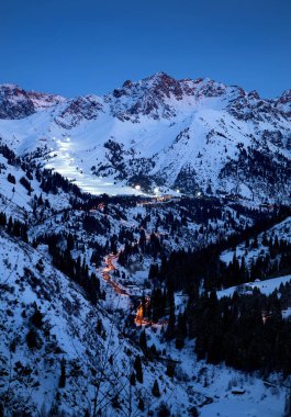 Landscape of glowing road from Medeu ice skate to Shymbulak ski resort at Tian Shan mountains at evening time in Almaty, Kazakhstan clipart