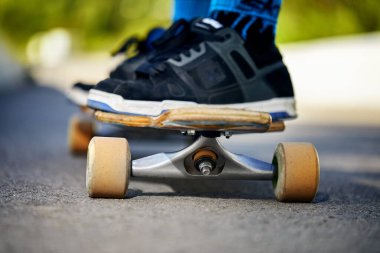 Man Skater at his longboard at mountain road close up shot at morning bright sunlight