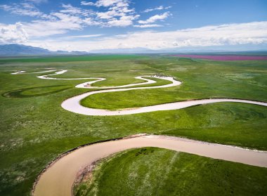 Dağ Vadisi, Kazakistan 'da gün batımında yeşil tepeli güzel manzaralı Kegen nehrinin insansız hava aracı görüntüsü. Otlakta beslenen at sürüsü.
