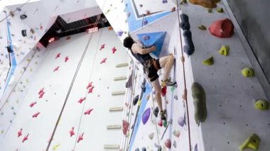 Siyah gömlekli adam, güvenlik sistemi ve iple kapalı bir duvarda antrenman yapıyor ve tırmanıyor.