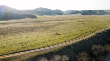 İHA, Güney Kazakistan 'da günbatımında yeşil bozkırda koşan atletler Ili nehrinin hava görüntüsünü çekti. Doğa manzarasında yol yarışması