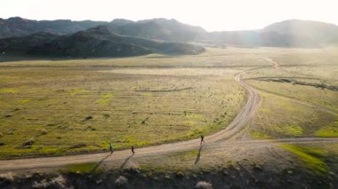 İHA, Güney Kazakistan 'da günbatımında yeşil bozkırda koşan atletler Ili nehrinin hava görüntüsünü çekti. Doğa manzarasında yol yarışması