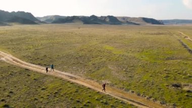 İHA, Güney Kazakistan 'da günbatımında yeşil bozkırda koşan atletler Ili nehrinin hava görüntüsünü çekti. Doğa manzarasında yol yarışması