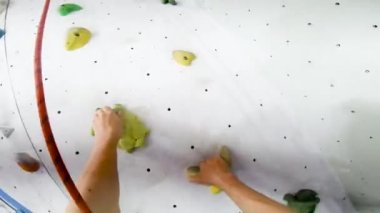 Siyah gömlekli adam, güvenlik sistemi ve iple kapalı alanda kaya duvarına tırmanıyor ve antrenman yapıyor. Başındaki kameradan bakış açısı