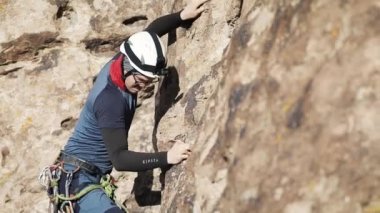 Mavi şortlu ve kasklı adam Kazakistan 'daki Ili Nehri' nde güvenli bir iple yüksek kayaya tırmanıyor.