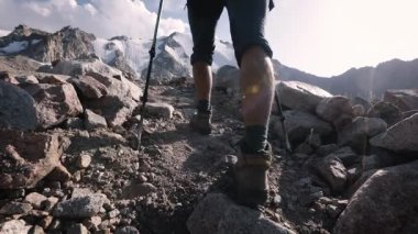 Sakallı erkek yürüyüşçü turist, büyük sırt çantalı ve buz dağı vadisindeki kayalıklarda yürüyen yürüyüş direkleriyle. Açık hava ve yürüyüş konsepti.