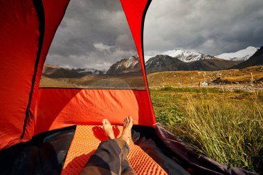 Çadırın içinden ve dağcıların bacaklarından dağlara, buzullu vadilere, Orta Asya Kazakistan ve Almaty 'de yürüyüş manzarasına bakın.