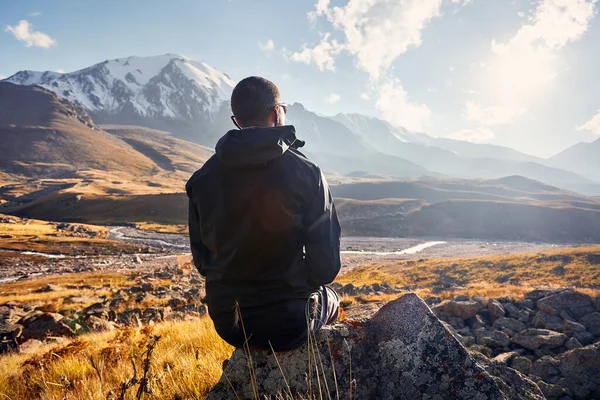 穿着黑色夹克的年轻男子形象远足游客坐在岩石上 面对着山谷中美丽的落日 户外及远足的概念 — 图库照片