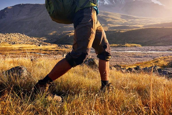 哈萨克斯坦阿拉木图 背着背包的观光客带着白雪的山峰漫步在秋天的山谷里 有鞋底的腿 — 图库照片