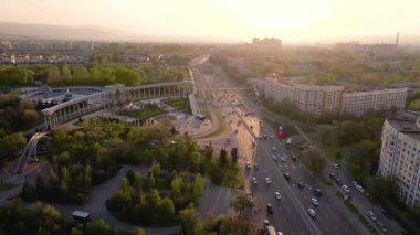 Almaty, Kazakistan 'daki ilk başkanın parkına girişi gösteren hava aracı görüntüsü. Baharda gün batımında trafik arabalarıyla Alfarabi Bulvarı.