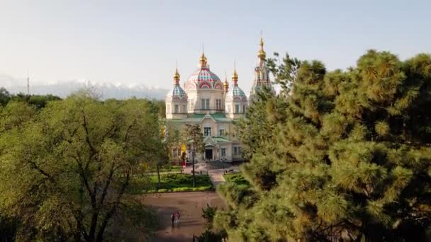 アセンション大聖堂の空中ドローンパノラマロシア正教会とアルマティ市 カザフスタンのPanfilov公園の背景に雪の山 — ストック動画