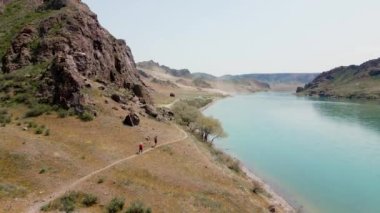 İHA, Ili Nehri 'nin bahar bozkırını ve Güney Kazakistan' da kırmızı tişörtlü iki patika koşucusunu görüntüledi..