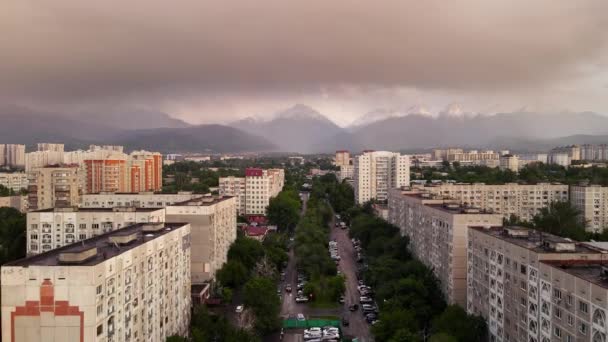 超高層ビルの空中ドローンビューパノラマ建物やアルマトイ市 カザフスタンの日没時に紫色の雲と雪の山の風景 — ストック動画