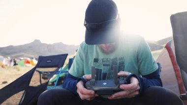 Drone operatör pilotu doğa kampında uzaktan kumanda tutuyor. Ağır çekim çekimini kapat