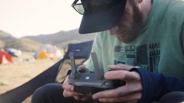 Drone operatör pilotu doğa kampında uzaktan kumanda tutuyor. Ağır çekim çekimini kapat
