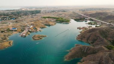 Güney Kazakistan 'da Kapchagay Gölü' ndeki küçük kayalık adaların ve beyaz teknenin hava manzarası gün batımında çekiliyor..