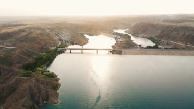 Güney Kazakistan 'da Kapchagay Gölü' ndeki küçük kayalık adaların ve beyaz teknenin hava manzarası gün batımında çekiliyor..