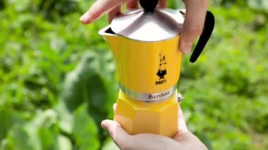 Sarı moka demliği, yaz mevsiminde yeşil dağ kampında buharlı kahve yapar. Sabah pikniği, doğada kahvaltıda sıcak içecek pişiren kişi..