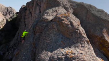 Atina 'nın yeşil gömlekli insansız hava aracı Orta Asya, Kazakistan' daki Ili nehrindeki yüksek kayaya tırmanıyor.