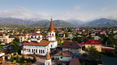 Gün batımında Almaty, Kazakistan 'daki kar dağlarına karşı ortodoks kilisesinin insansız hava aracı görüntüleri.