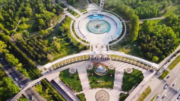 从空中俯瞰通往哈萨克斯坦阿拉木图第一总统公园的入口拱门和圆形喷泉 Alfarabi大道 春天日落时的交通车辆 — 图库视频影像