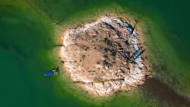 空中スタンドアップパドルボードSupで女性の空中ドローンショットダウン カザフスタンのカチャガイ湖に海鳥のいる小さな岩の島日没時 — ストック動画
